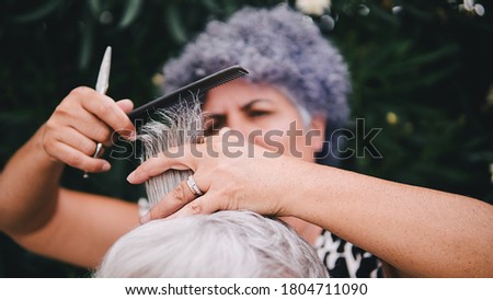 Stock photo of white woman with short white hair getting a haircut. The hairdresser is using the scissors.