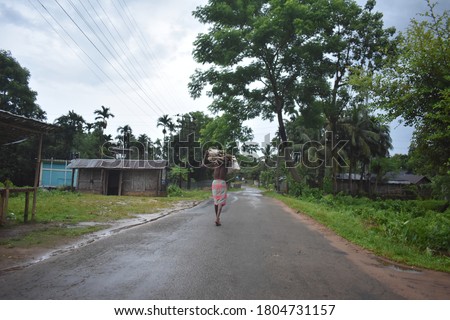 Man walking on a village road carrying some wood 
Waring gamcha 
this is a image of east India rural village man carrying wood for his house 
