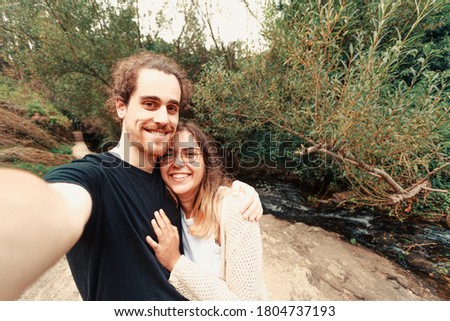 A young couple taking a selfie near a river in Spain