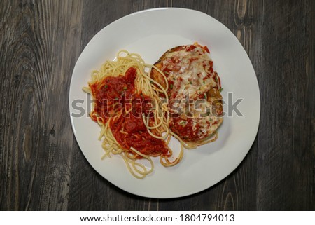 Top view of eggplant parmesan and spaghetti with marinara sauce.