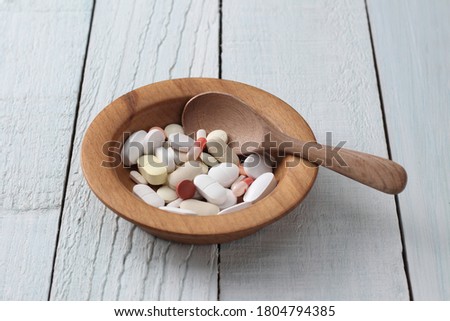 tablets and capsules in a wooden bowl.