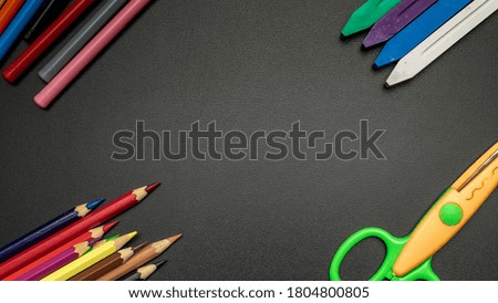 Education concept. School stationery with colorful pencils, chalk, brushes on black chalkboard in classroom. Banner Concept Back To School.