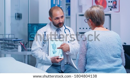 Old woman getting medical advice about osteoporosis bones disease from experienced doctor in private clinic sitting on hospital bed. Patient healthcare treatment and health consultation Royalty-Free Stock Photo #1804804138