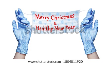 Doctor hands blue rubber medical gloves, surgical protective mask, snowflakes pattern, Merry Christmas & Healthy New Year text white background isolated closeup, coronavirus protection, holiday banner