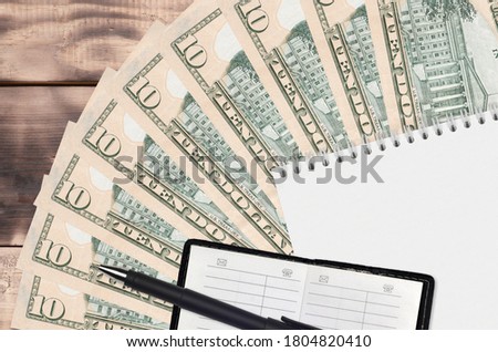 10 US dollars bills fan and notepad with contact book and black pen. Concept of financial planning and business strategy