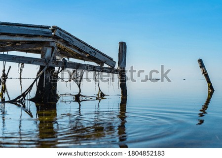Abandoned pier remains on a beach looking out to the mediterranean ocean. Relaxing background screensaver. Save the planet concept. Save the oceans. Wooden pier. Mirror water limitless.