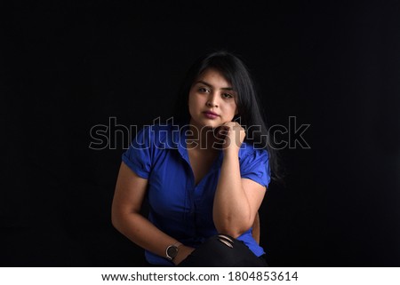 portrait of a latin woman sitting on chair and looking at camera on black background, 