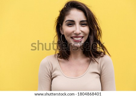 Young woman laughs. Beautiful brunette. Yellow background. Close-up. 