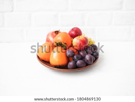 Autumn composition with fresh fruits. Apple, plum,  persimmon, pomegranate, 
grapes. Selective focus.