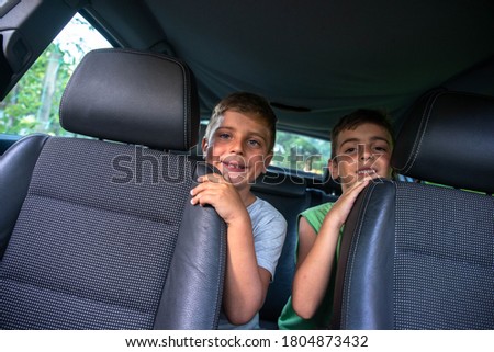 Two boys are sitting in the back seat of the car