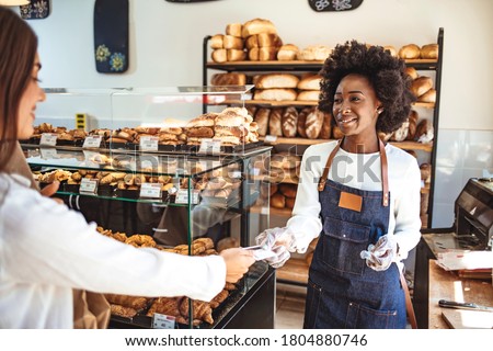 Customer making a credit card payment in a bakery. Paying with credit card for a baguette. Paying by credit card in the store with bakery products. Paying with a credit card in the bakery 