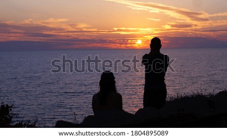 a guy and a girl look at the sunset on the sea