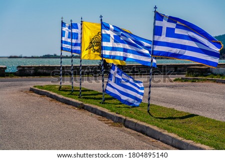 A waving Greek flags at the wonderful coastal village of Aitoliko in Aetolia-Acarnania, Greece with blue sky background on sunny Spring day.