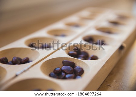 Traditional indian board with game tamarind seeds - aluguli mane aata - selective focus background Royalty-Free Stock Photo #1804897264