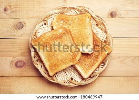 Toast bread in a wicker plate on wooden background. Top view Royalty-Free Stock Photo #180489947