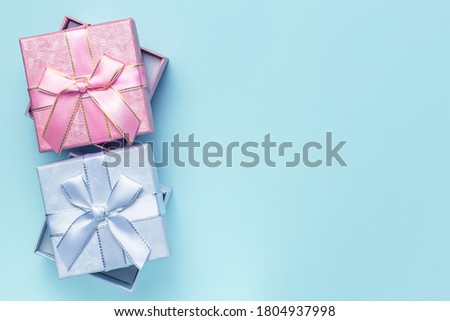 Festive greeting banner, poster for sale, gift wrapping, beautiful box of pink lilac color with bows from ribbons for the holiday on a blue background in pastel colors with copy space top view flatlay