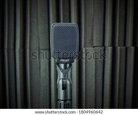 Front view of dynamic microphone for vocals and choirs mounted on stand, gray, on acoustic foam background