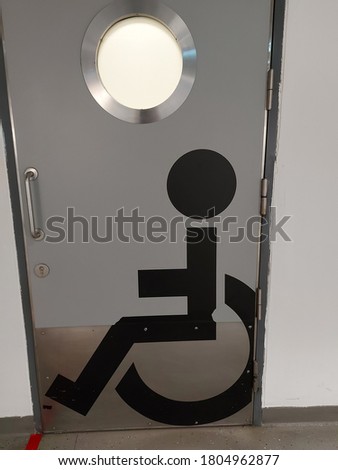 A toilet door in a mall has a handicap symbol.