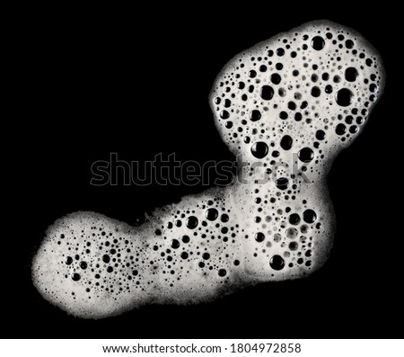 Spilled beer puddle with foam isolated on black background and texture, top view, clipping path