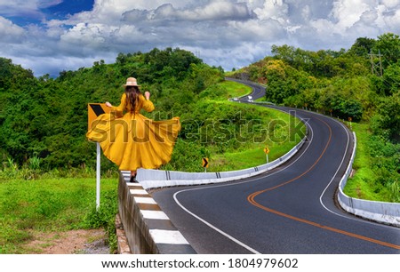Asian tourist woman walking alone on country road rear view. Number three of road among the mountains at Nan, Thailand