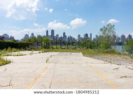 Vacant Land on the Riverfront of Astoria Queens New York with Overgrown Plants and a view of the Roosevelt Island and Manhattan Skylines Royalty-Free Stock Photo #1804985212