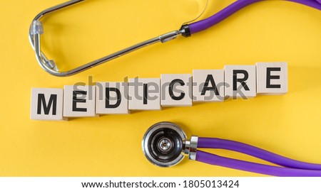 Medicare word written on cube shape wooden blocks on yellow table with stethoscope Royalty-Free Stock Photo #1805013424