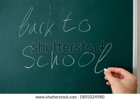 
hand writes on the blackboard in the classroom go back to school