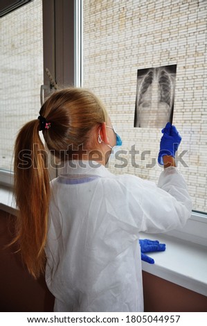 a girl plays doctor and treats her Teddy bear, a doctor in a white coat looks at a picture of the lungs