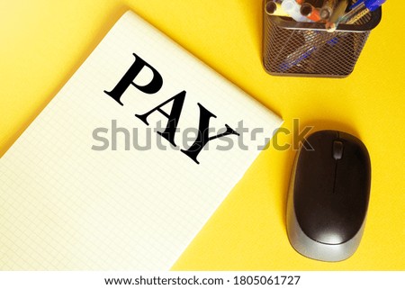 computer mouse, pens, felt-tip pens, notepad with text Pay on a yellow background