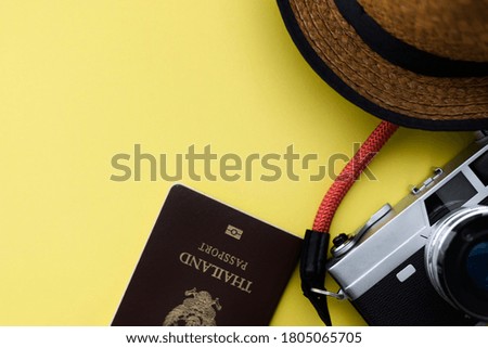 Flat lay travel with passport, camera, hat on yellow background