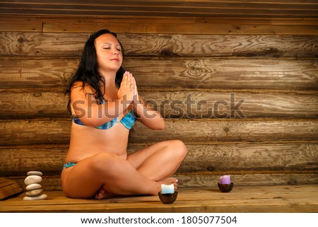 Young brunette woman sits in a bath, meditates on namaste.