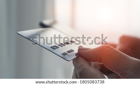 Woman hands holding a blue credit card selective focus on card number and using a smartphone for shopping online or internet banking. Online shopping concept.