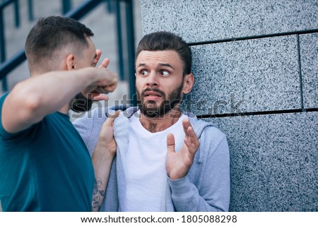 Two adult bearded men are fighting in the street. Conflict, bullying, robbery. Royalty-Free Stock Photo #1805088298