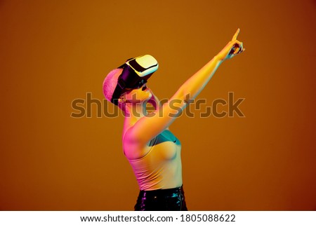 Young caucasian woman on brown studio background in neon light