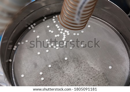 Lots of white tablets are poured onto a special sieve. Abstract medical picture. Background image