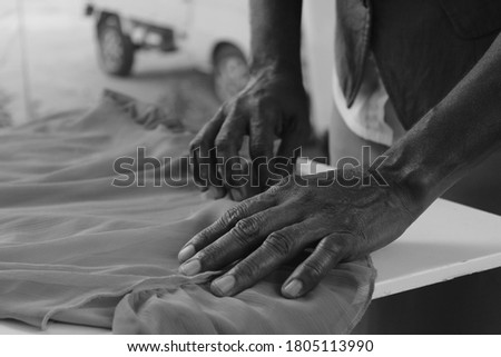 Wrinkled hands of an elderly seamstress