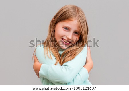 Closeup portrait, confident smiling woman, holding, hugging herself, isolated gray background. Positive human emotion, facial expression, feeling, reaction, situation, attitude. Love yourself concept