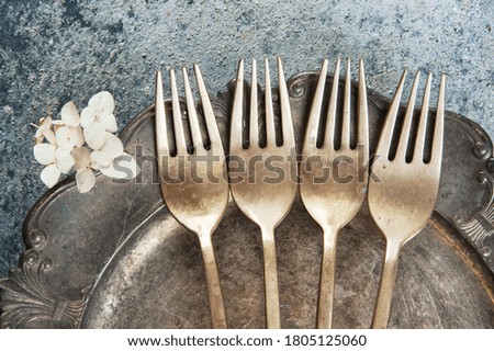 Old bronze forks on vintage dish on concrete background. Copy space for text, food photography props.