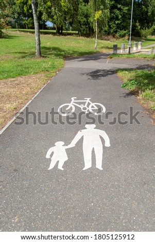 a cycling and pedestrian shared path sign painted on a pathway