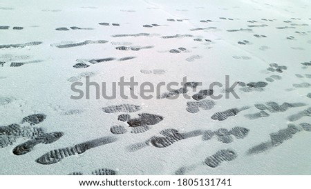 Blurred photo of snow covered asphalt. Footprints in the snow. Snowy road and footprints. Snow covered asphalt surface