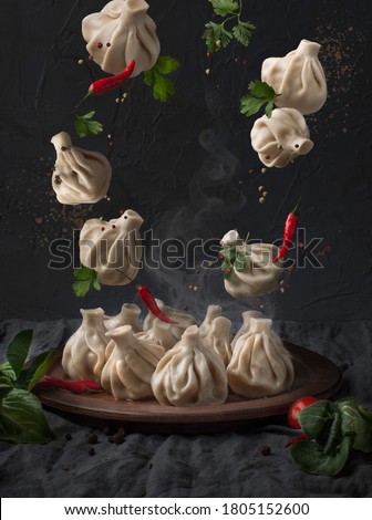 traditional georgian flying khinkali with spices on dark background. Food levitation concept. Royalty-Free Stock Photo #1805152600