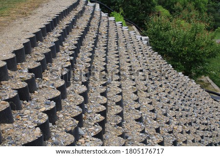 Ground surface stabilized with perforated geo cells filled with gravel stones. Geo web support. Slope protection, erosion control and soil stabilization. Selective focus. Shallow depth of field. Royalty-Free Stock Photo #1805176717