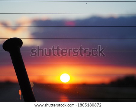 Softball bat with orange and purple sunset in the background.