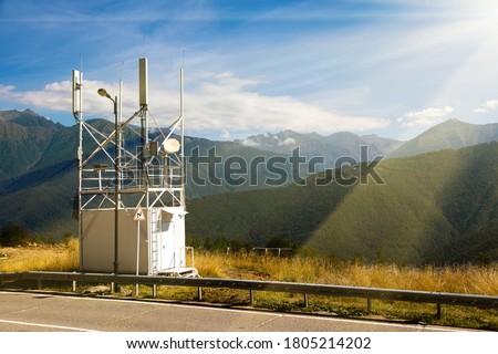Telecommunications transmitters 4G, 5G. cellular base station with transmitter antennas near a road on the background of mountains.