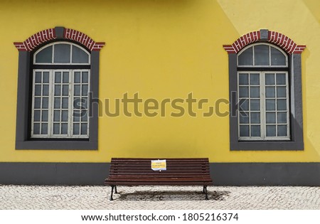 Bench in the street of Faro,with a warning sign,bench painted fresh,wall patterns behind