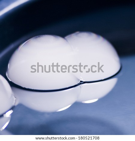 Abstract shot with big soap bubbles on a water surface with smoke inside. Image has grain texture visible on its maximum size