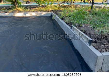 The base for tiling is prepared using a membrane that suppresses the growth of weeds and prevents mixing of rubble and earth. Selective focus.
 Royalty-Free Stock Photo #1805250706