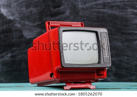 Red retro old school portable mini tv set on blackboard background Royalty-Free Stock Photo #1805262070
