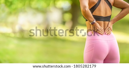 Back pain during sports. Young woman with an athletic figure and a lower back injury. Royalty-Free Stock Photo #1805282179