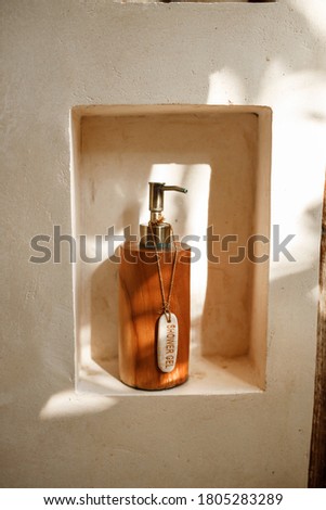 Wooden bottle of shower gel  on the shelf of bath in modern hotel room with textured white  wall